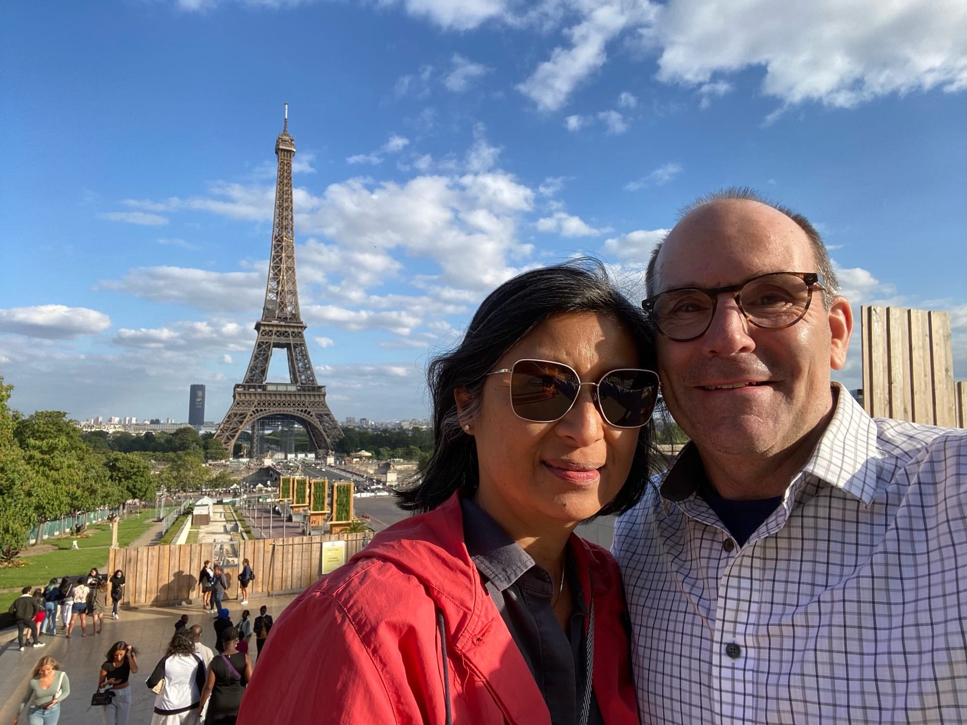 Couple poses in front of the Eiffel Tower with a blue sky above