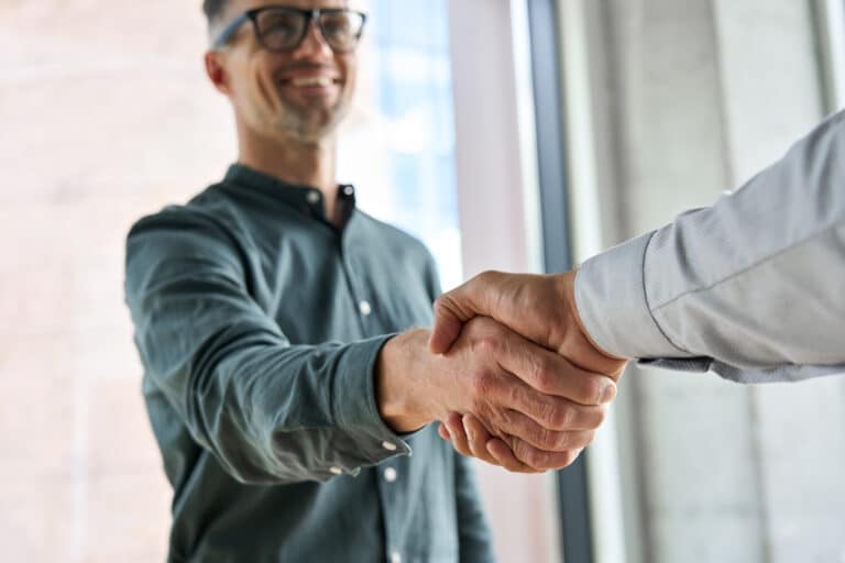 Two happy professional businessmen shaking hands at meeting