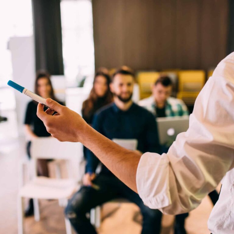 hand holding marker as person lectures small group